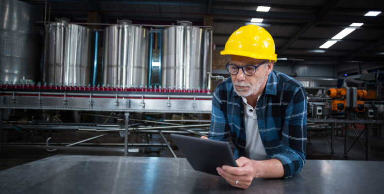 Factory worker using digital tablet at drinks production factory